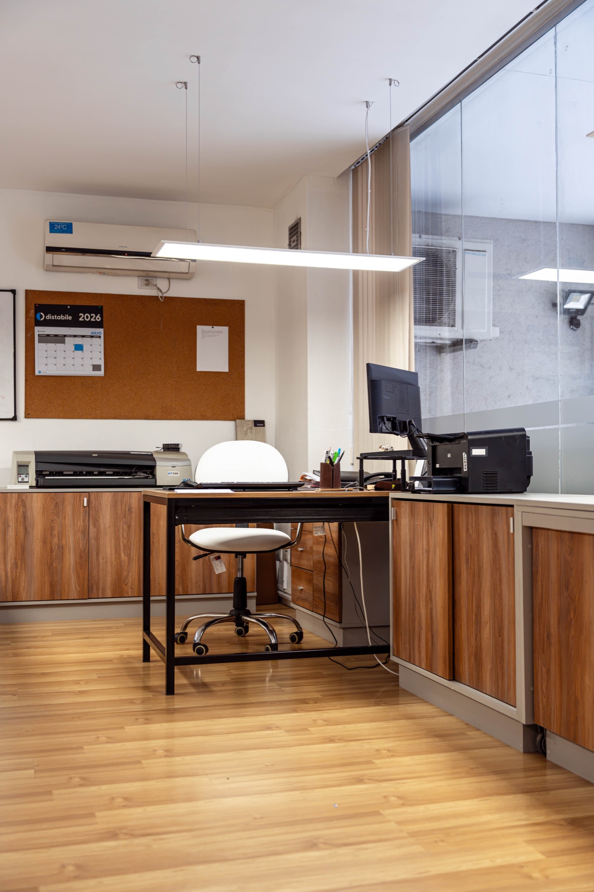 Puesto de trabajo con escritorio de hierro y madera, muebles bajos y luminaria suspendida